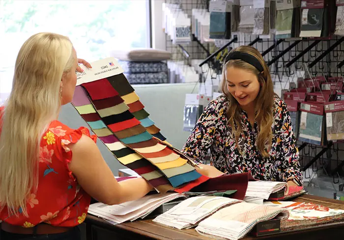Textiles, Leathers & Vinyls 12 Finish Pros designer reviewing Made in the USA velvet upholstery fabrics with a client in the Raleigh, NC showroom. Furniture Restoration Consultant