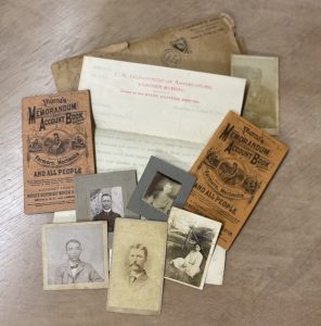 A collection of antique documents, including sepia-toned photographs, handwritten letters, and vintage account books from the 19th century, discovered in a concealed compartment of the restored bureau desk.