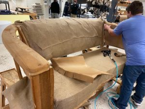 Restoration process of a vintage channel-back sofa with new ivory boucle fabric being carefully applied by Finish Pros experts.