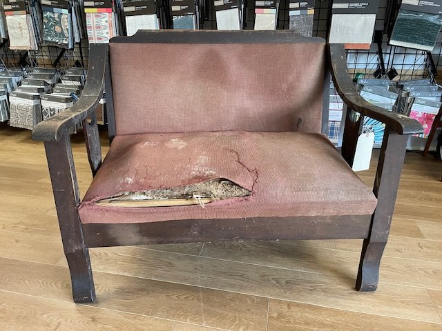 Victorian settee with torn upholstery and exposed straw padding before restoration at Finish Pros