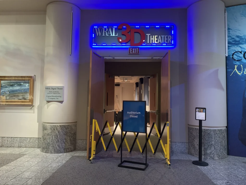 Entrance to the WRAL 3D Theater in Raleigh’s Museum of Natural Sciences with ‘Auditorium Closed’ signage during Finish Pros' commercial reupholstery and restoration project.
