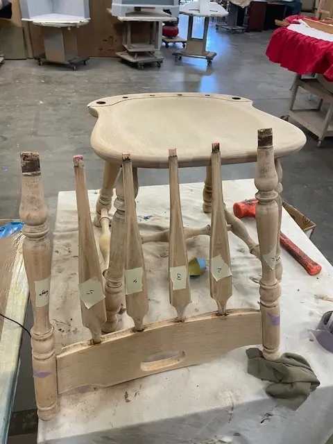 Disassembled Kling maple chair with labeled spindles during regluing process to repair loose joints at Finish Pros furniture restoration shop.