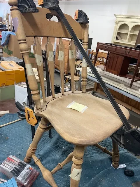 Kling maple dining chair clamped on a flat work surface during regluing to ensure level seating, part of restoration process at Finish Pros in Raleigh NC.