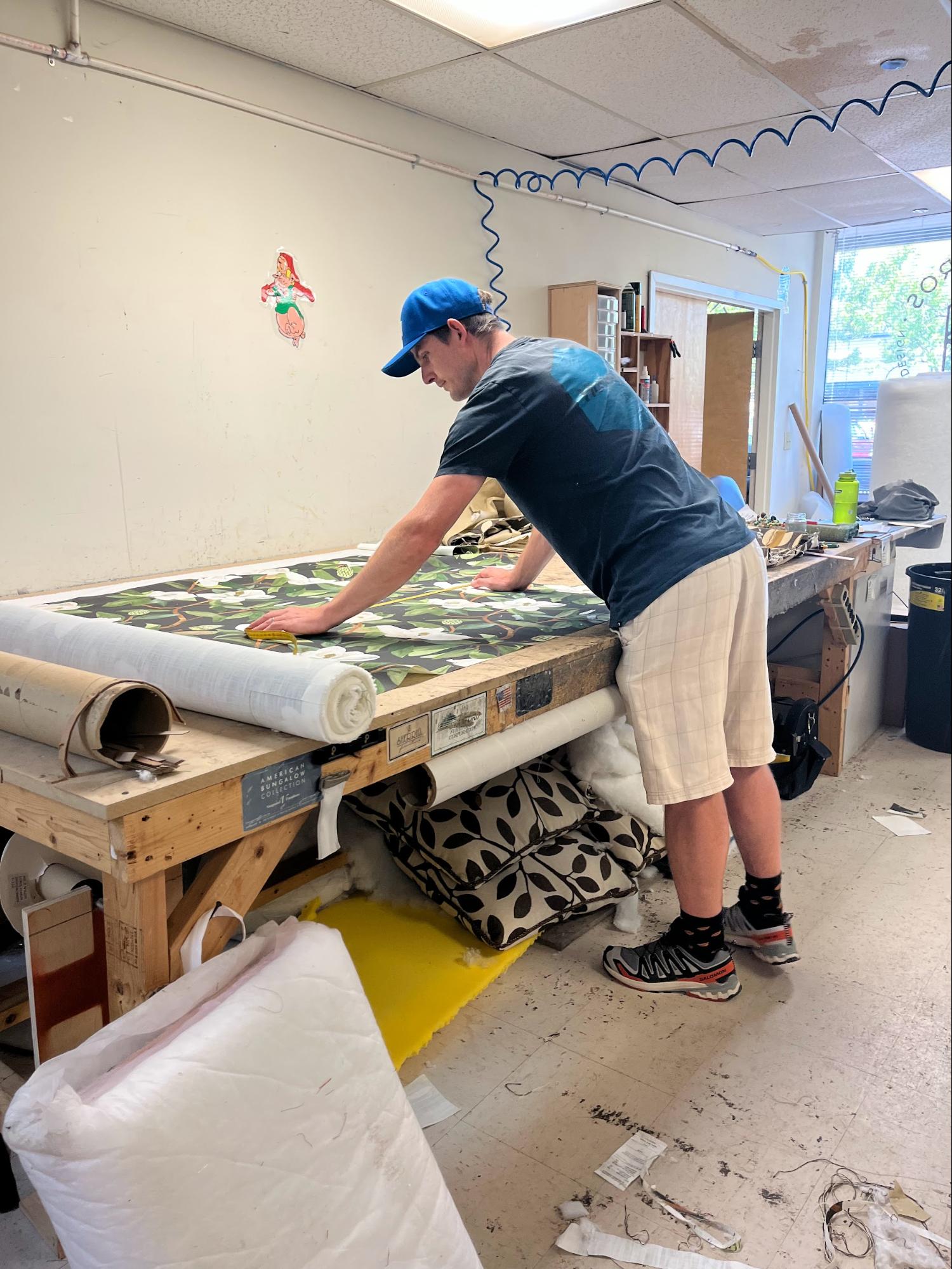 Upholstery fabric being measured and cut for a custom furniture reupholstery project.