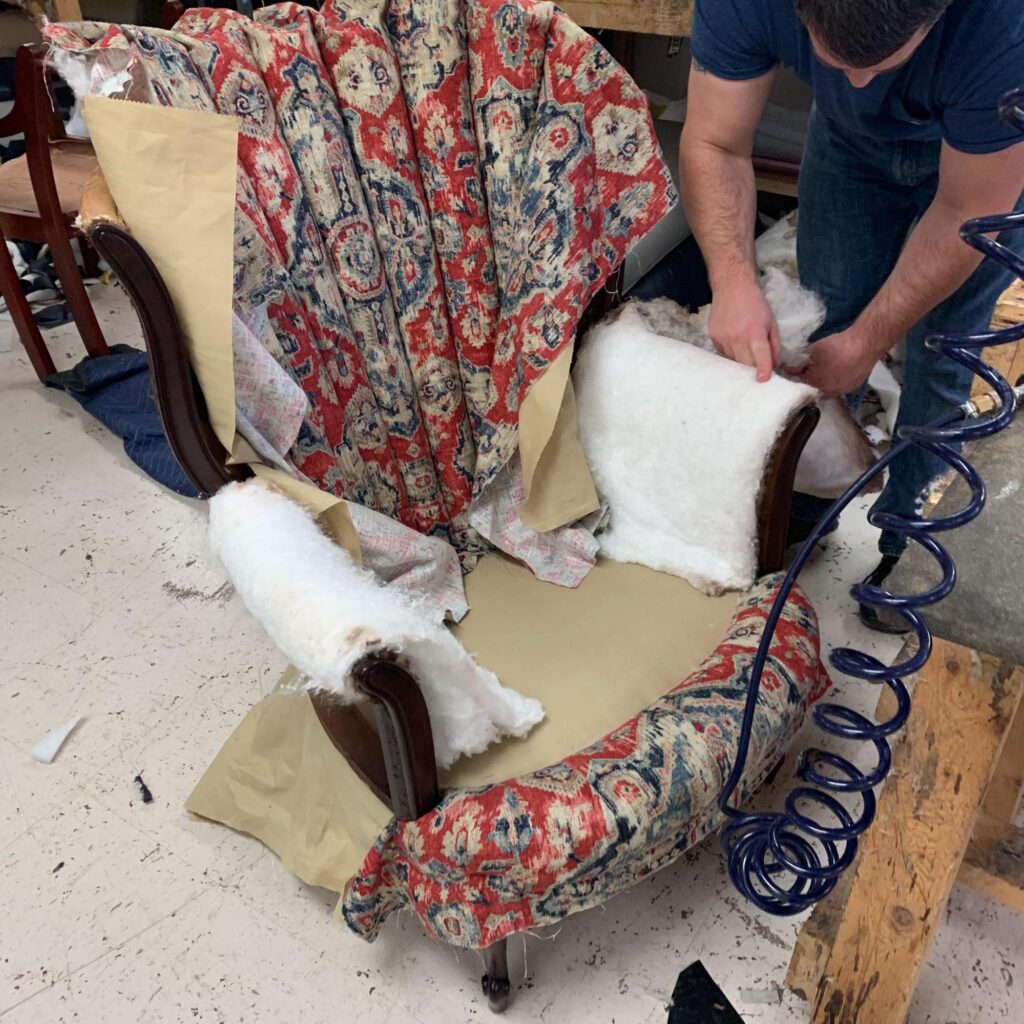 The Art and Craft of Master Upholstery: Finish Pros and Master Craftsmanship in North Carolina 3 Master upholsterer at Finish Pros installing fabric on a custom upholstered chair in Raleigh, NC