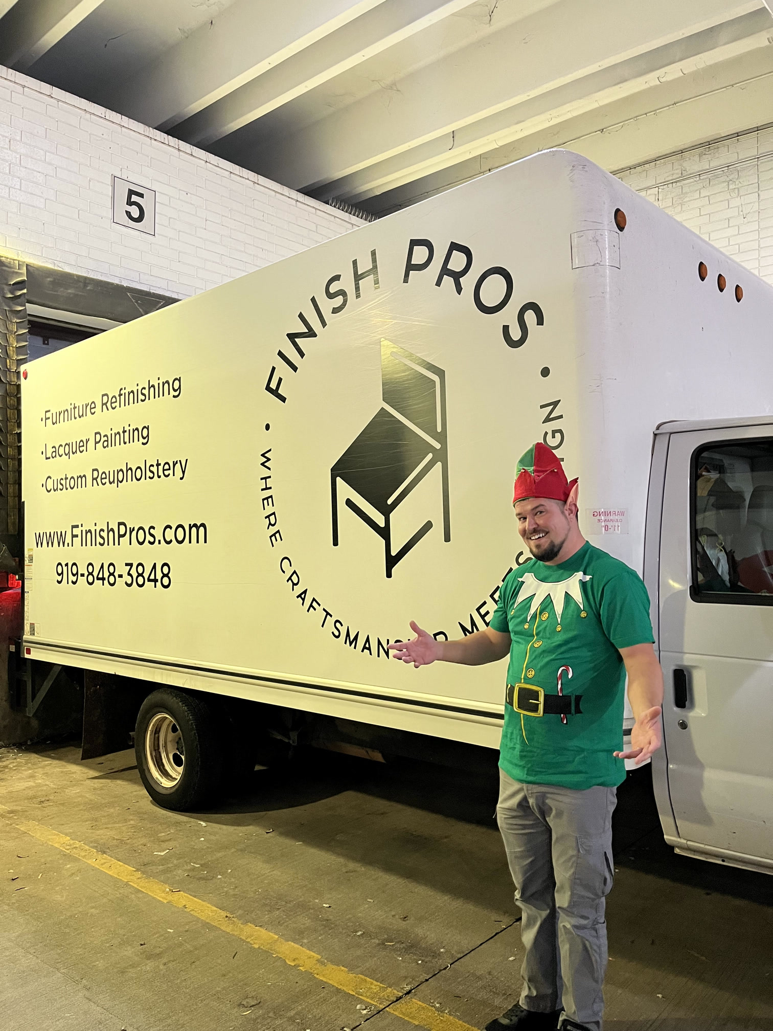 Finish Pros delivery team member Scott dressed as a holiday elf, standing beside the branded delivery truck ready for a seasonal furniture restoration drop-off.