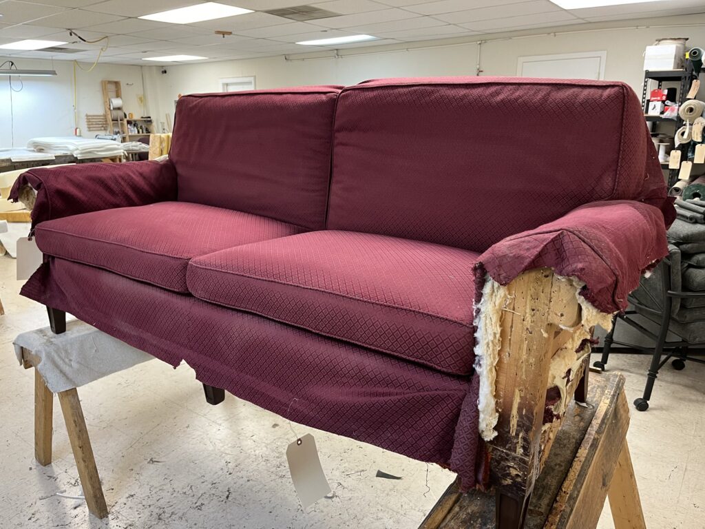 Sofa Cushion Foam Replacement Solutions: Restore Comfort & Support with Finish Pros 2 Burgundy sofa undergoing a full reupholstery job in Raleigh, NC, including new foam cushions and custom fabric installation, captured mid-process in Finish Pros workshop.