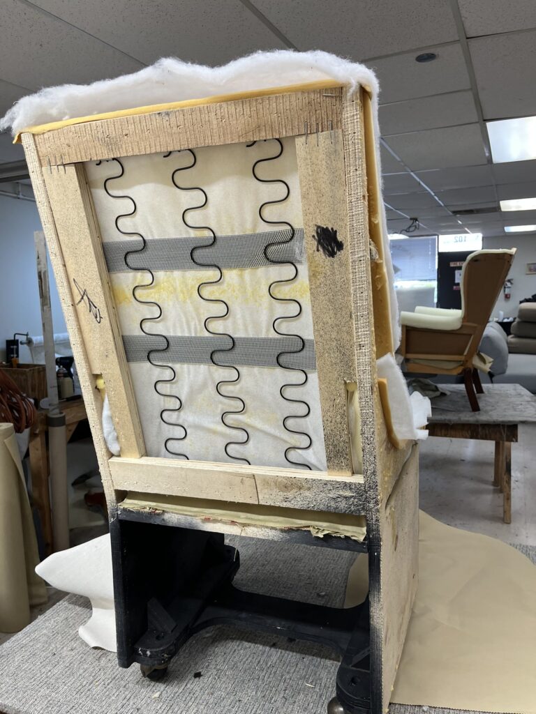 The Art of Reupholstery: How Finish Pros Transforms Raleigh Furniture with Craftsmanship and Care 4 Before image: Parsons chair undergoing complete reupholstery by Finish Pros—stripped to the frame with exposed springs and padding, ensuring structural integrity before installing new foam and fabric.