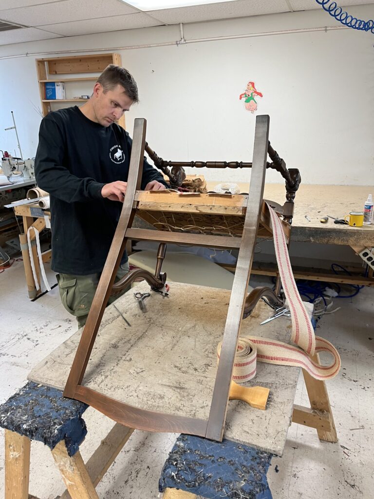 What to look for in quality furniture 8 A Finish Pros upholsterer working on the internal structure of a vintage chair during reupholstery. This stage focuses on reinforcing the frame, webbing, and support system to ensure long-term comfort and durability before new upholstery is applied.