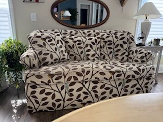 What Reupholstery Costs in Raleigh, and the 7 Things That Move the Price 2 Curved-back sofa in cream and brown leaf-print fabric before reupholstery, Finish Pros Raleigh NC