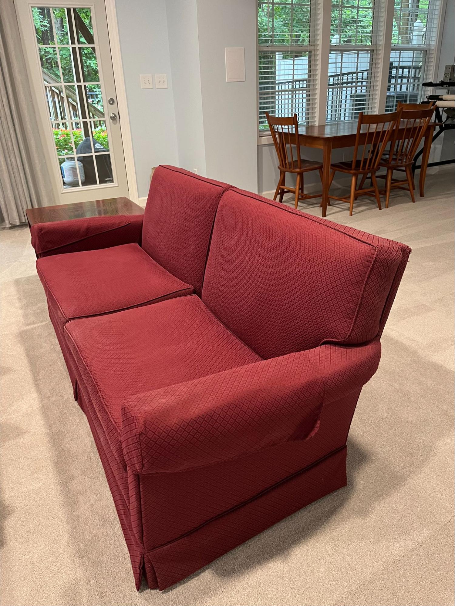 Red skirted two-cushion sofa before reupholstery by Finish Pros in Raleigh NC